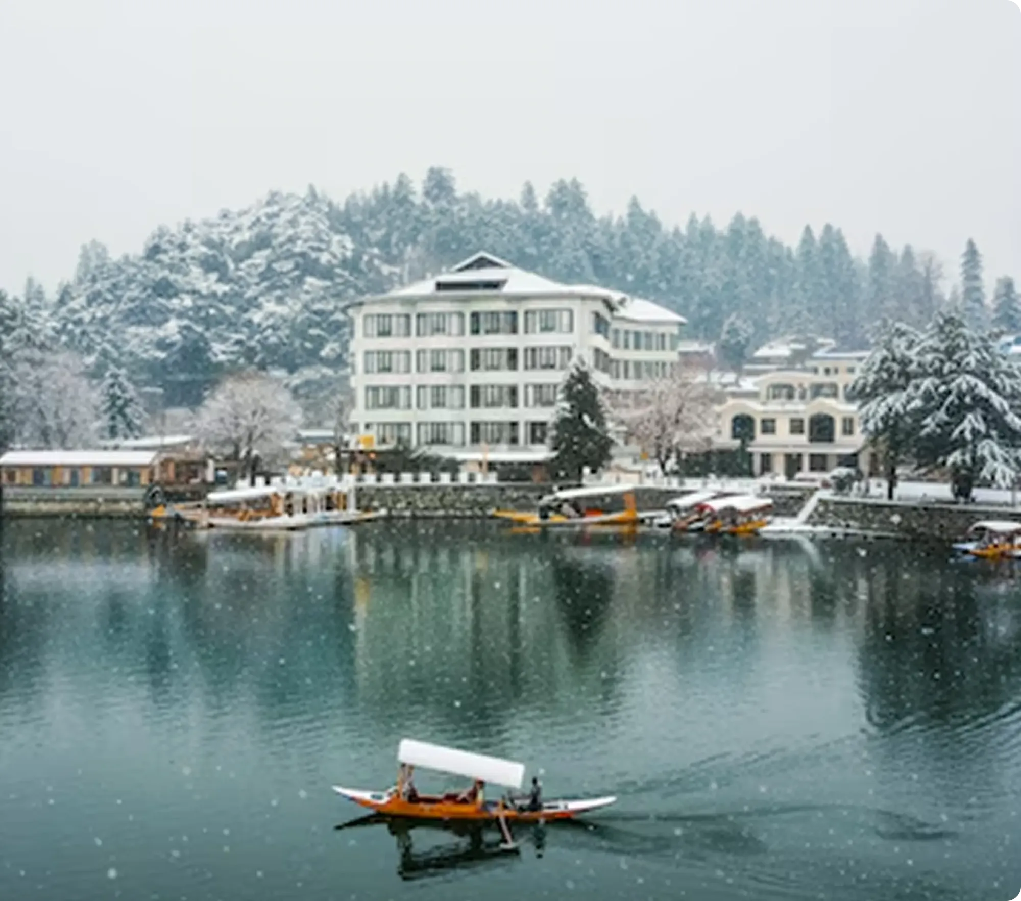 The hotel by a lake in the snow, with a shikara on the water
